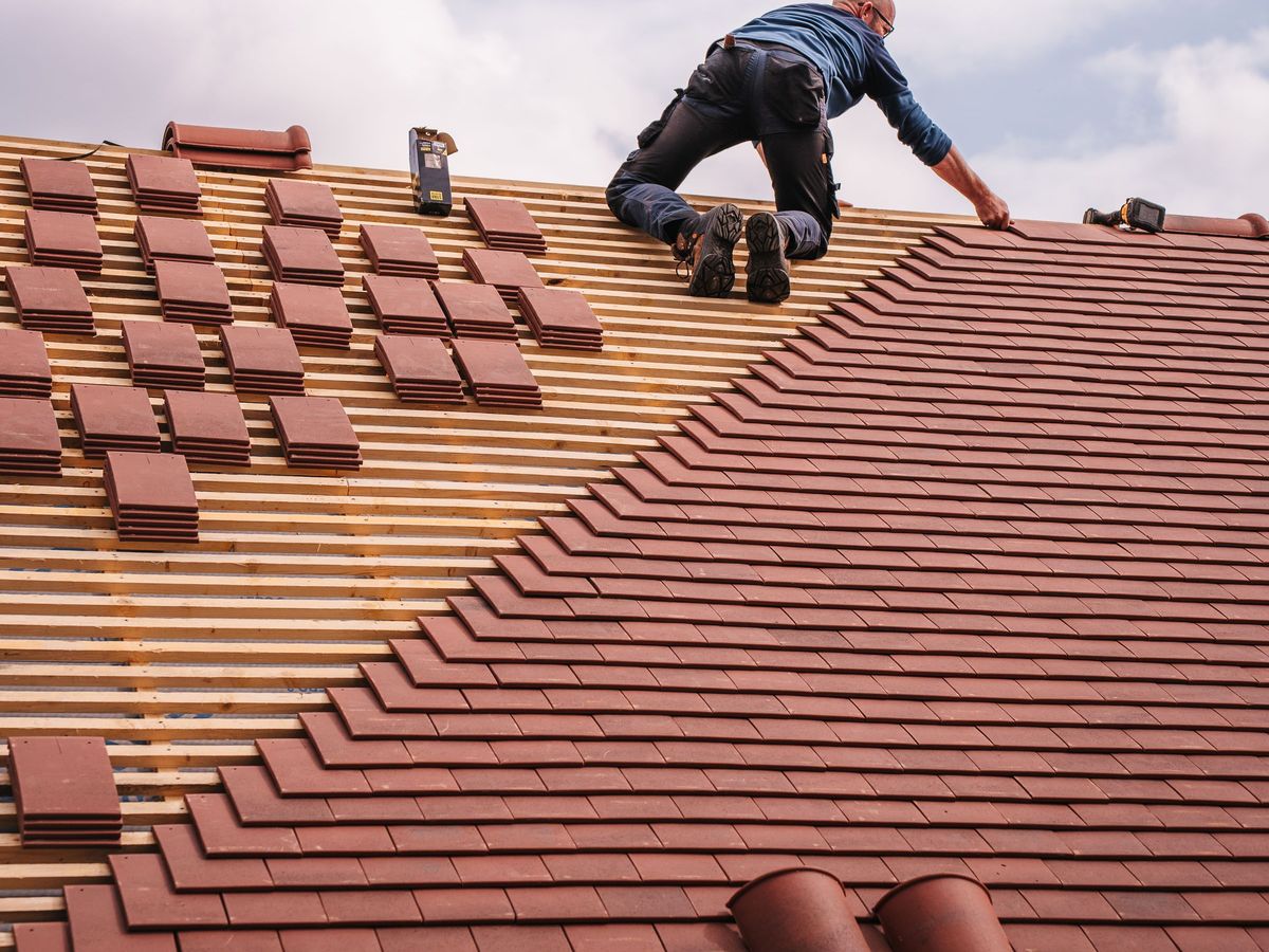 Roofer laying terracotta tiles on a residential roof